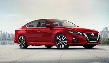 2023 Nissan Altima in red with city in background illustrating last year's 2022 model in Cherokee County Nissan in Holly Springs GA